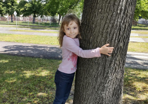 Dziewczynka przytula się do drzewa